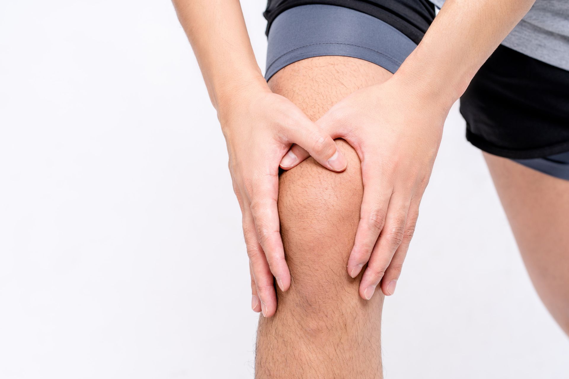 Twee handen op knie in verband met pijn aan knie
