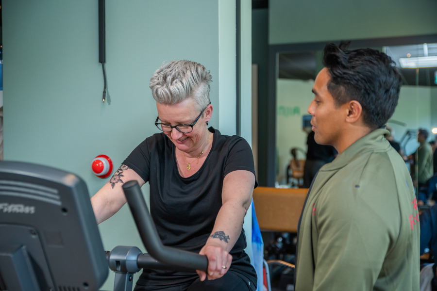Mevrouw op crosstrainer bij fysiotherapeut